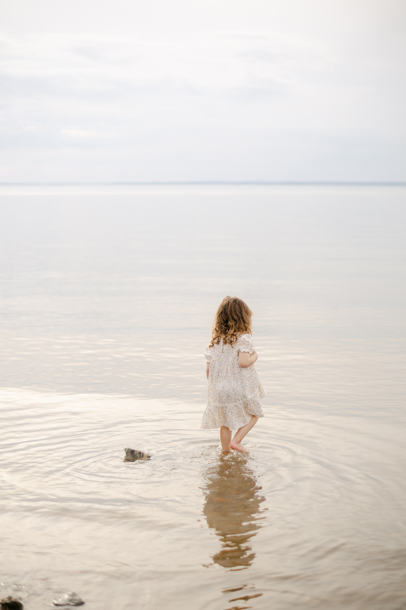 Toddler Girl in dress stands in peaceful waters