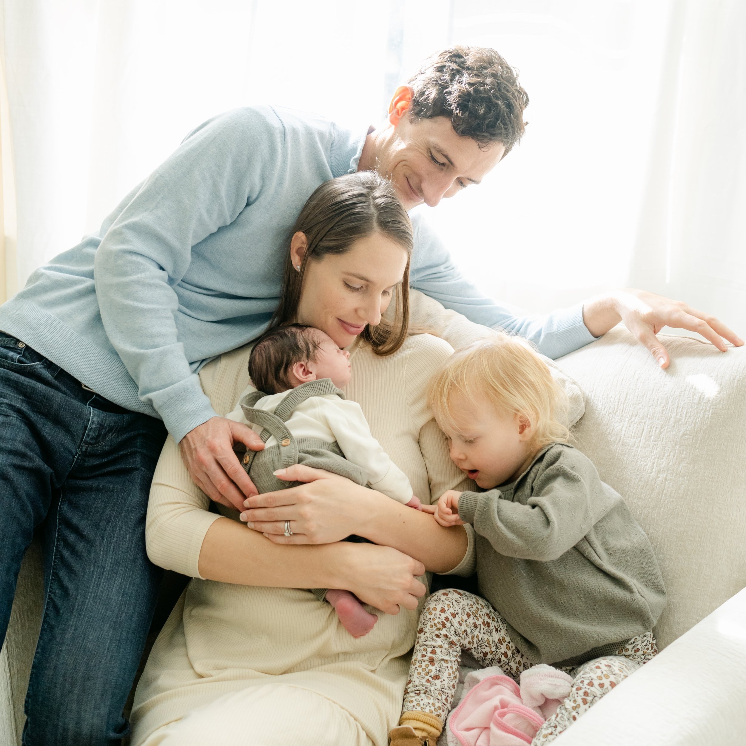 Family cuddles their newborn baby and toddler in their home outside of Philadelphia.