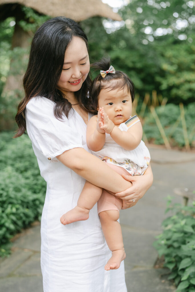 Dark-haired mother holds toddler girl in Wilmington gardens