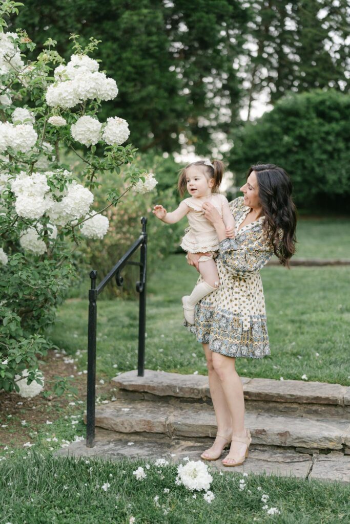 mother holds daughter at Winterthur gardens next to white hydrangeas