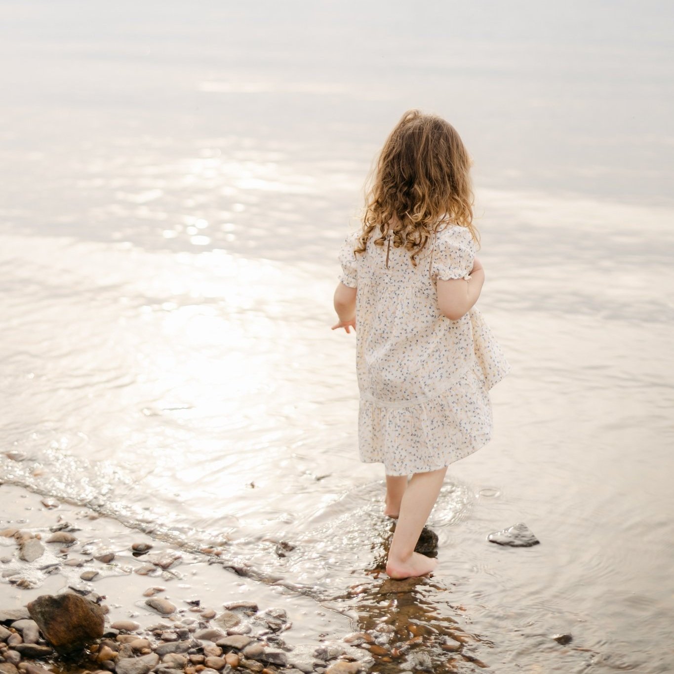 Little girl with a sundress wades in the water on the Chesapeake Bay in Maryland