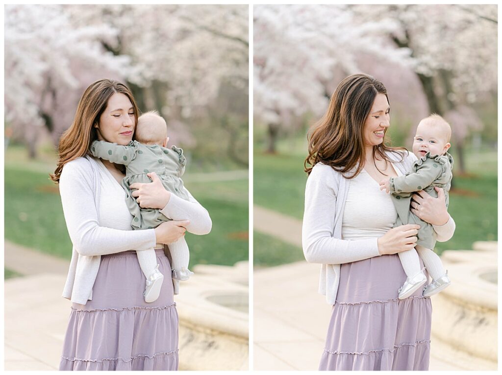 Mother holds baby with spring trees in the background
