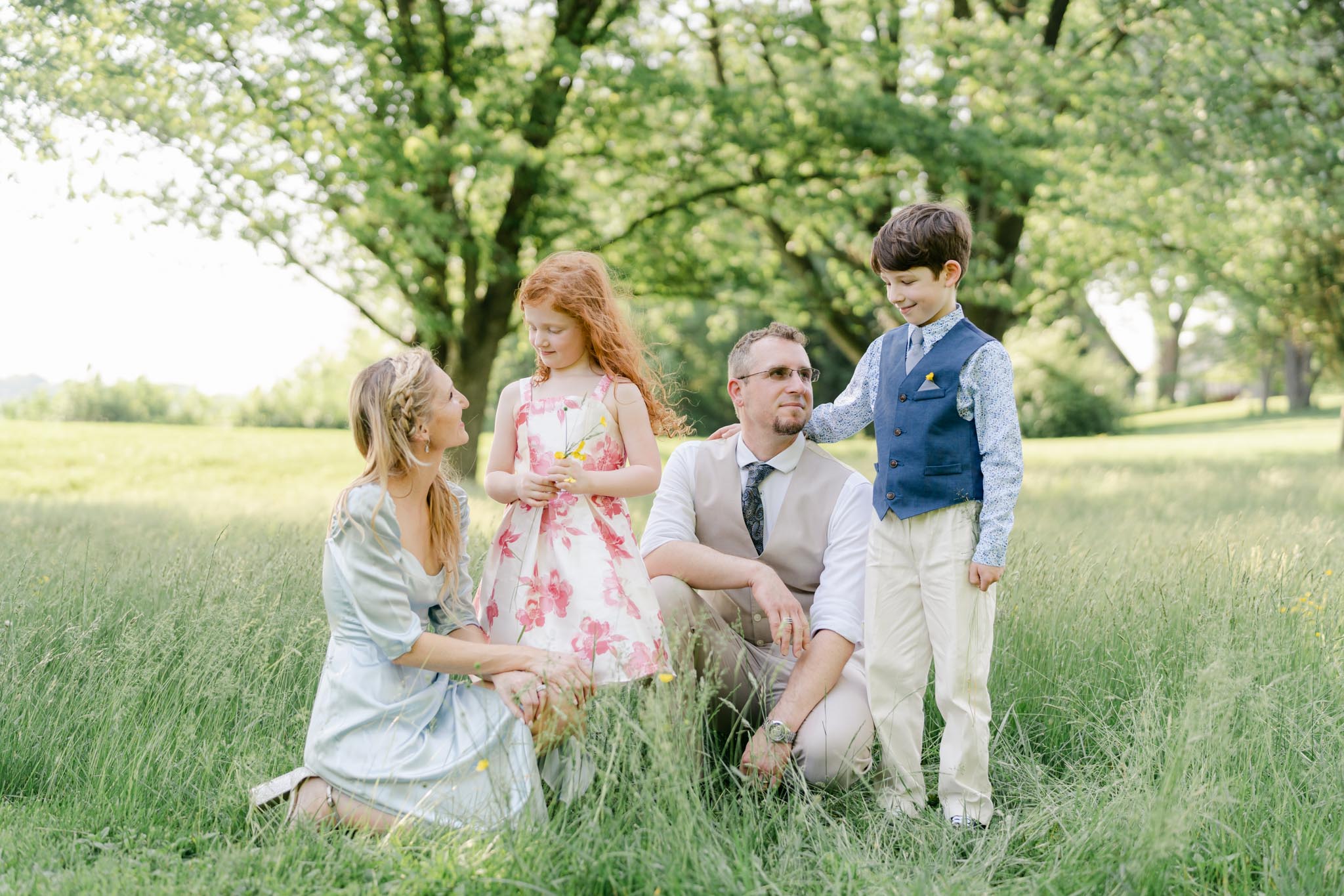 family of four kneeling in the grass in a field