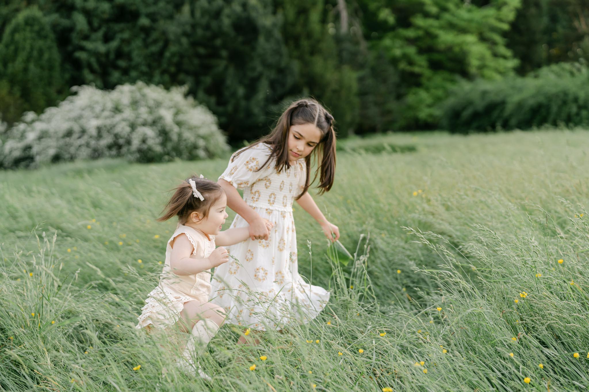 Sisters running through a field of grass holding hands Pediatricians in Wilmington DE