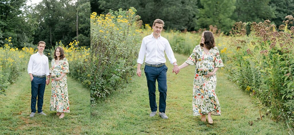 expecting husband and wife holding hands while walking through wildflower field
