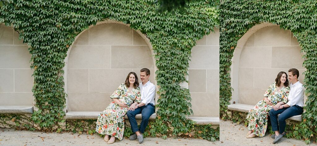 husband and wife sitting under a greenery arch while snuggled together