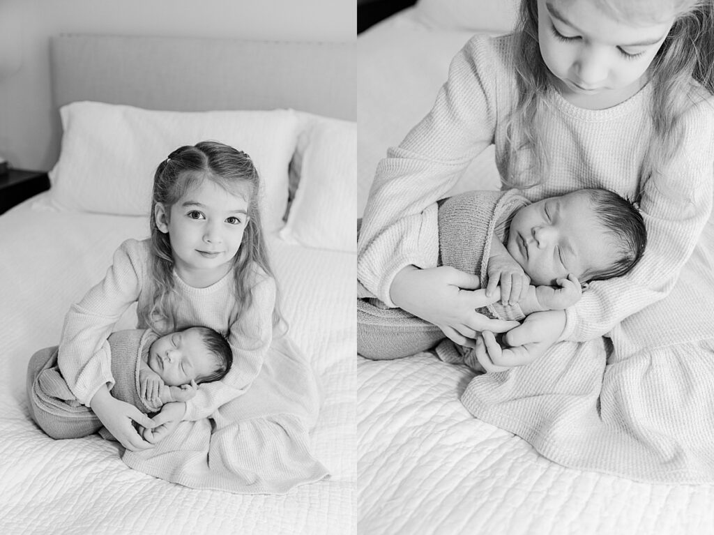 black and white image of big sister holding baby brother while swaddled in a blanket