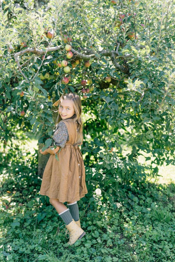 Girl in linen dress picks apples at Barnard Orchard in Kennett Square, PA
