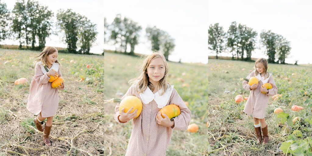 Little girl in linen dress happily picks pumpkins in an Amish pumpkin patch near West Chester PA