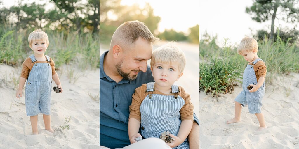 Young boy in pinstriped overalls walking through the sand with a pinecone in hand and snuggled up to his father