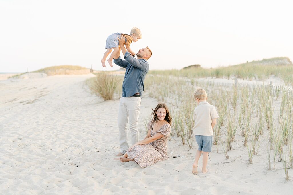 A family of four sitting on the beach by Rehoboth Beach Family Photographer, AnneMarie Hamant