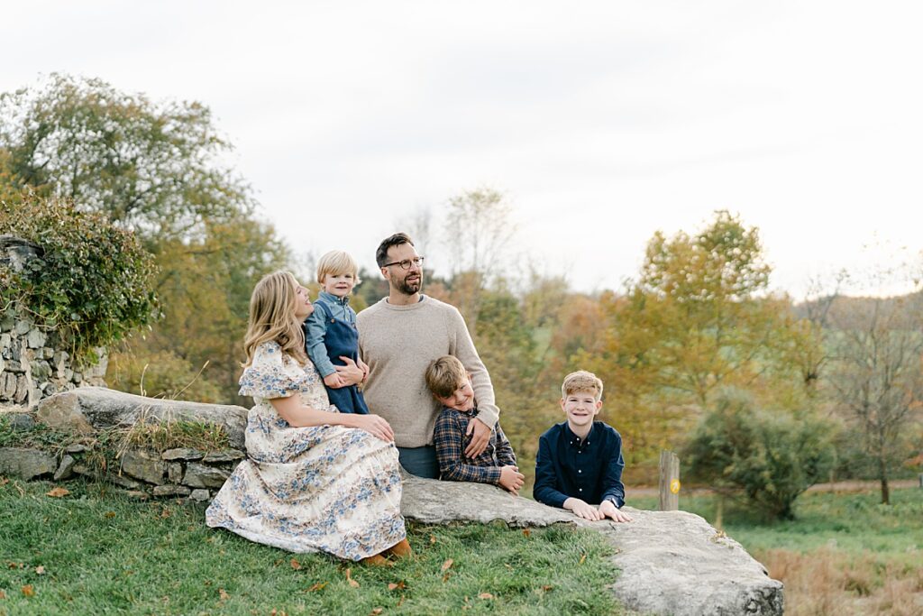 A family of five sitting on a stone wall looking off into the distance by philadelphia portrait photographer, annemarie hamant