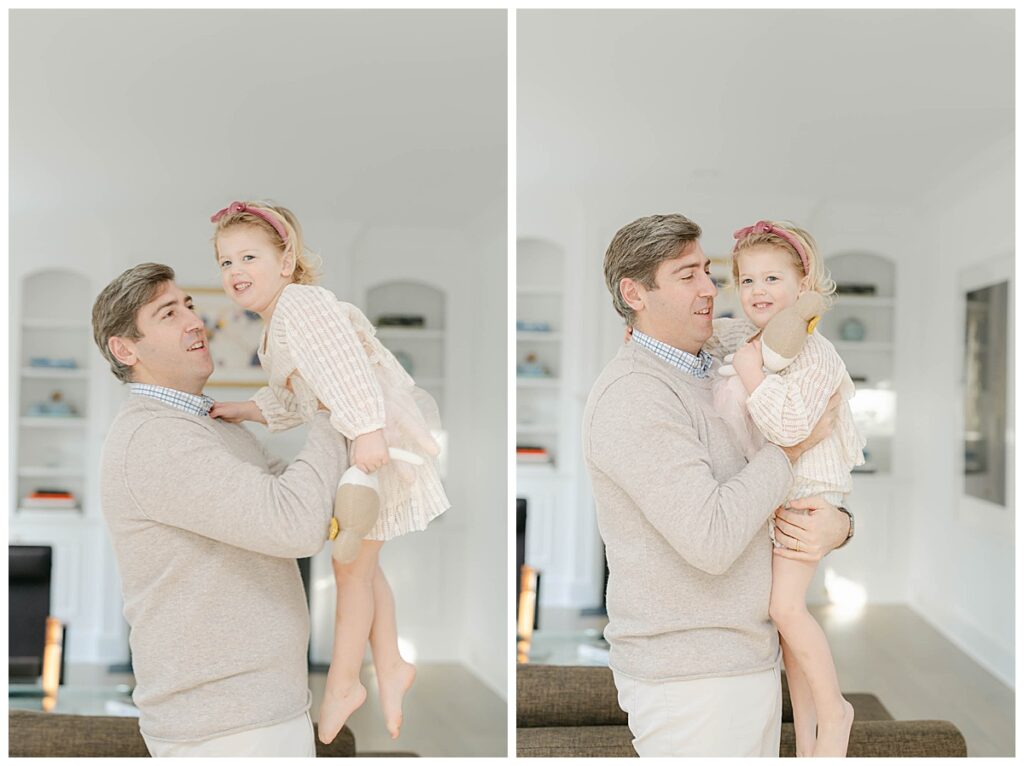 Dad in beige holds toddler daughter up in the air