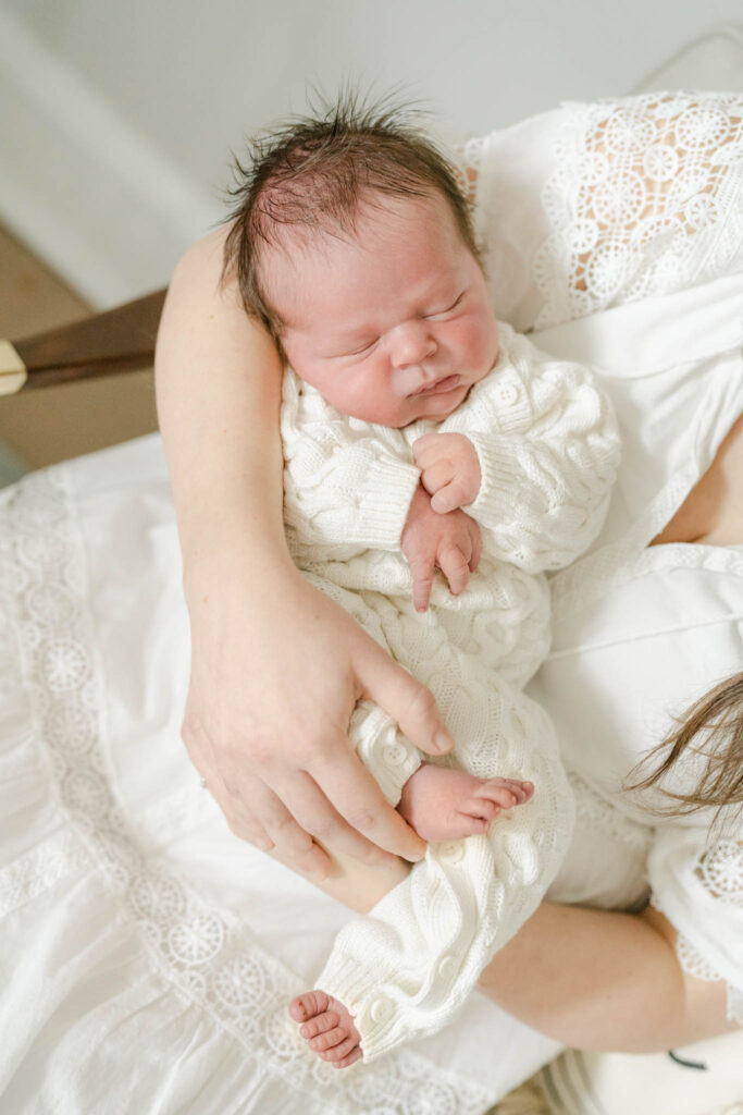 Newbor Baby in white sweater snuggled up in his Philly nursery