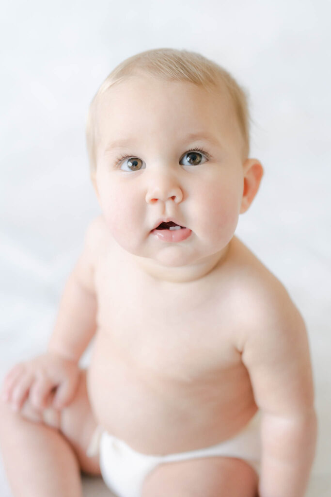 baby girl in white diaper on a light backdrop