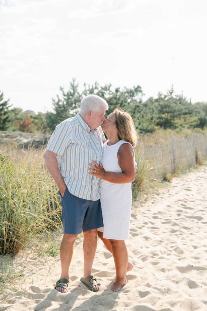 Older couple kisses on the beach in Bethany Beach Delaware during an extended family photo session