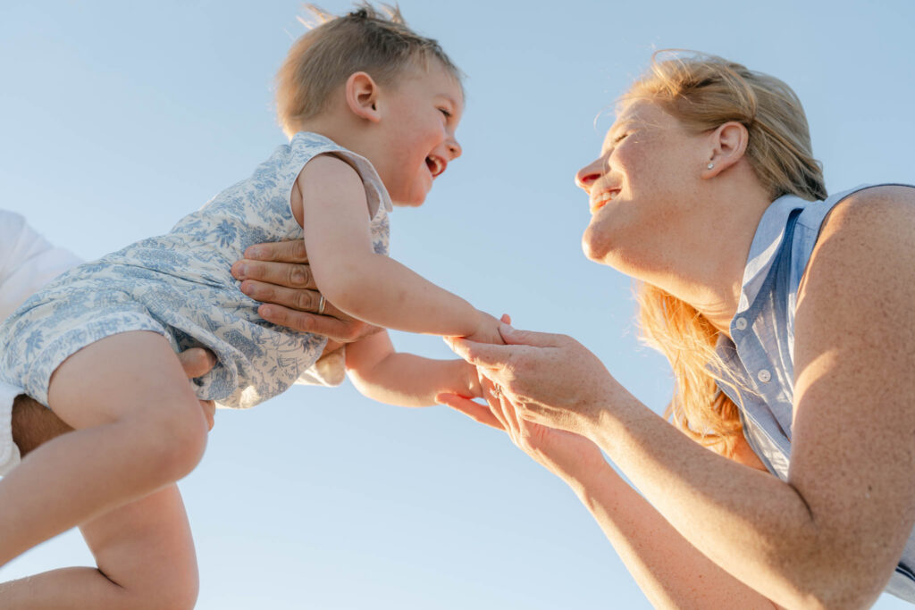 mom reaches for toddler son at sunset photo session in Bethany Beach