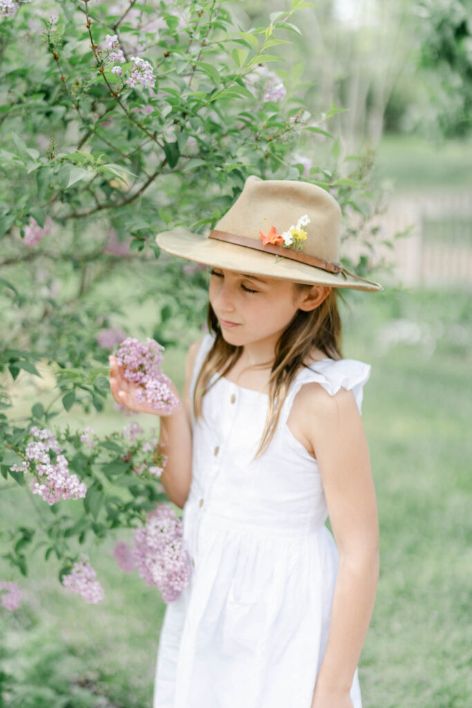 Girl in white dress smells spring lilacs at a garden in Philadelphia