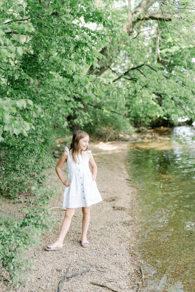 Girl in white dress stands near water at Bartram gardens