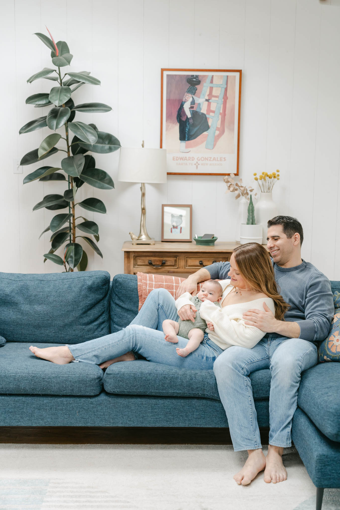 Couple poses with new baby on their couch during a Wilmington DE newborn session