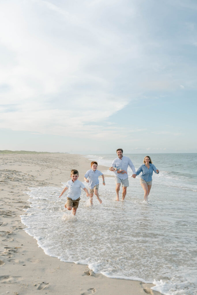 family runs in the ocean at the beach